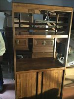 Front view of wooden bar cabinet with wine glass rack and shelving below