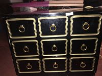 Front view showing three rows of drawers with gold-tone ring pulls and scalloped rectangular inlaid trim on the drawer fronts.