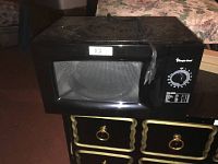 Front view of the black Magic Chef microwave oven showing the control dial timer and power control knob attached to the microwave door.