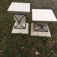 Pair of outdoor patio pedestal stands on grass showing tops and bases with metal frame accents