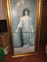 Full view of the framed print showing a woman in classical attire holding a rod, with iridescent effect on the print and the entire gold wooden frame visible.