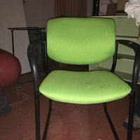 Front view of green chair with metal arms and legs showing fabric upholstery and black frame.