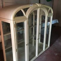 Front and angled view showing the glass doors, rounded top, and blonde oak finish of the hutch.