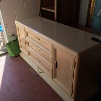Front view of the wooden dining cabinet showing three central drawers and two side doors with brass handles.
