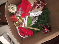 Top view of box containing a variety of Christmas decorations including garland, candle holders, gift bags, and decorative plates.