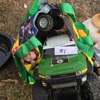 Photo of toy vehicles inside colorful bag, showing green Toyota toy truck and silver and black truck with large wheels.