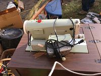 Kenmore sewing machine mounted on wood table with cords wrapped around it and visible control knobs.