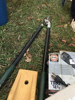 Photo showing long-handled pruning shears and wooden boot remover on grass next to the drill box and plastic container of hardware
