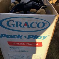 Box showing Graco Pack 'n Play Portable Playard branding and features such as removable bassinet, quilted bumper pad, mesh ventilation, folding changing table, electronic sounds and lights.