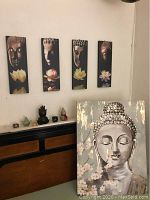 Dresser top showing four narrow Buddha canvas panels and group of decorative items