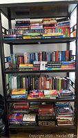 Photo showing several shelves filled with a wide variety of books, stacked both vertically and horizontally, showcasing a range of titles and authors