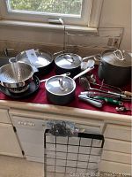 Full assortment on countertop beneath window: cookware, colander, rack, utensils