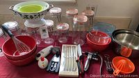 Wide view of all items including storage jars, mixing bowls, colanders, kitchen tools, and boxed steak knives on table