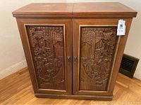 Front view of closed wooden bar cabinet with ornate Asian carvings on doors, marble top closed