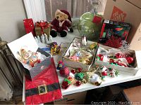 Wide view of entire lot showing ceramic cookie jar, porcelain figurines, plush bear, and multiple boxes of ornaments and decorations.