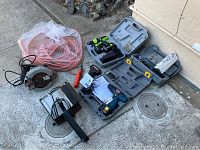 Wide view of all power tools and extension cord in lot: cordless drill, Dremel tool, table saw, heat gun, and extension cord.