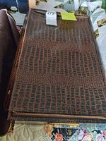 Closed brown faux crocodile texture zippered case holding silver plated flatware set.