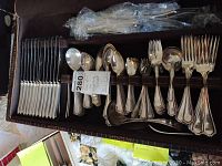 Open fitted leather case showing full flatware set inside.