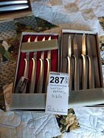 Two sets of Gerber knives, six knives in red-lined box and five knives in grey-lined box laid on quilted fabric surface