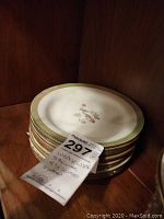 Stack of eight Wedgwood plates showing their size and detail in a wooden setting with auction tag.