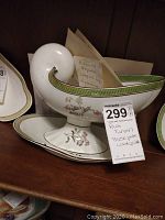 Soup tureen with attached base plate showing floral handpainted decoration and green border.