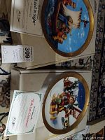 Two boxed Hummel collector plates with certificates of authenticity visible on top of the boxes.