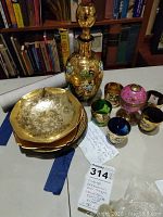 Photo of the Bohemian decanter, 5 gold-tone plates, and 5 decorated shot glasses with floral gold designs.