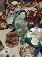 Overview of assorted Fenton and hand blown glass items on table including baskets, bowls, figurines, and decorative pieces