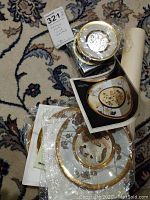 Three Asian decorative plates with gold edging, packaging, and informational brochures.