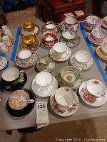 Overview of 16 assorted teacup and saucer sets arranged on table