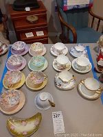 Overhead view of all 13 teacup & saucer sets, extra cup and candy dish arranged on table