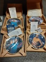 Photo showing all four Star Trek plates: Spock, McCoy, Kirk, and Piece of the Action, each in open cardboard holder and wrapped in plastic with certificates visible.