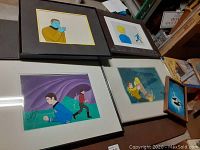 Overview of five framed animation cels on tabletop