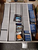 Full view of box with multiple stacks of Star Trek trading cards in sleeves and loose cards on top.