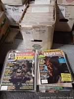 Box filled with a collection of magazines labeled Starlogs 1-100, with some visible magazine covers in front
