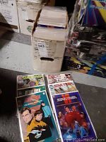 Photo showing 6 Star Trek comic books stacked in front of a filled comic book storage box.