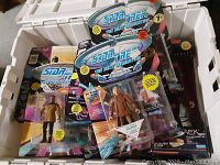 Multiple Star Trek: The Next Generation action figures new in box, stacked inside plastic bin.