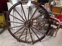 Full view of wagon wheel showing wooden spokes, metal rim, and hanging chain.