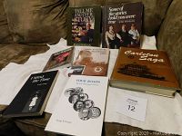 Photo showing collection of seven books arranged on a couch with their covers visible for identification.