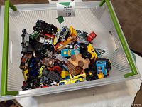 A plastic bin filled with more than 150 assorted used toy vehicles including cars, trucks and some planes.