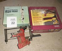 Lot showing original boxed General Purpose Rope Hoist and boxed Milescraft D/TT FeatherBoard alongside red Milwaukee chainsaw sharpener tool on floor.