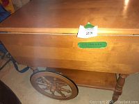 Side view of the tea cart showing wooden wheels, spindle legs, and finish.