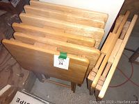 8 wooden TV trays stacked together showing tops and folding legs.