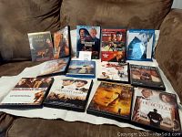 Photo of the 13 DVD cases displayed on a couch, showing various titles and cover art.