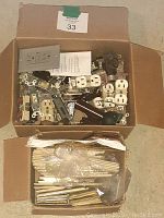 Box containing assorted used white electrical outlets, toggle switches, and matching face plates, along with some individual parts and hardware.