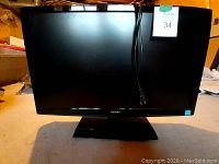 Front view of the Toshiba 24 inch TV monitor showing glossy black screen and Toshiba logo on the front bezel. Power cord is draped over the screen.