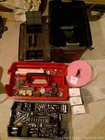 Open top trays showing assortment of sockets, wrenches in one tray and various hardware including nails and electrical parts in another red tray