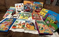 A collection of 15 used preschooler books laid out on a surface. Books include colorful board books and picture books featuring Disney characters, educational themes like shapes and colors, and other assorted titles.