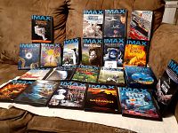 Photo of all 25 DVDs spread out on couch, showing cover art and titles of the IMAX documentaries and Oceans Alive box set with metal case.