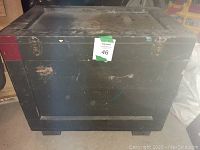 Closed dark green wooden box showing scratches and metal clasps